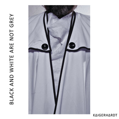 Piece of a bigger picture. To see is a chin with beard and a piece of a trench coat in white with black outlines and two black buttons for the kollar. Under the coat is a white linen shirt. font left side from down to up: black and white are not grey. font right down corner: kaigerhardt