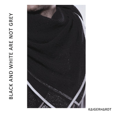 lightly woven black fabric with white outlines. a piece of a chin and neck with short beard hair. font left side from down to up: black and white are not grey. font right down corner: kaigerhardt