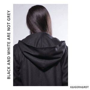 from the back, black jacket with hood, head with long dark hair, white wall