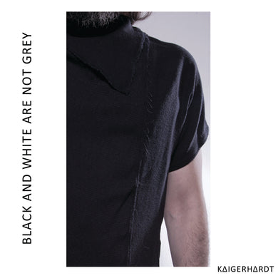 Zoom in picture of another picture. Man wears black t-shirt with raw edges. You see a bit of the beard and hair.