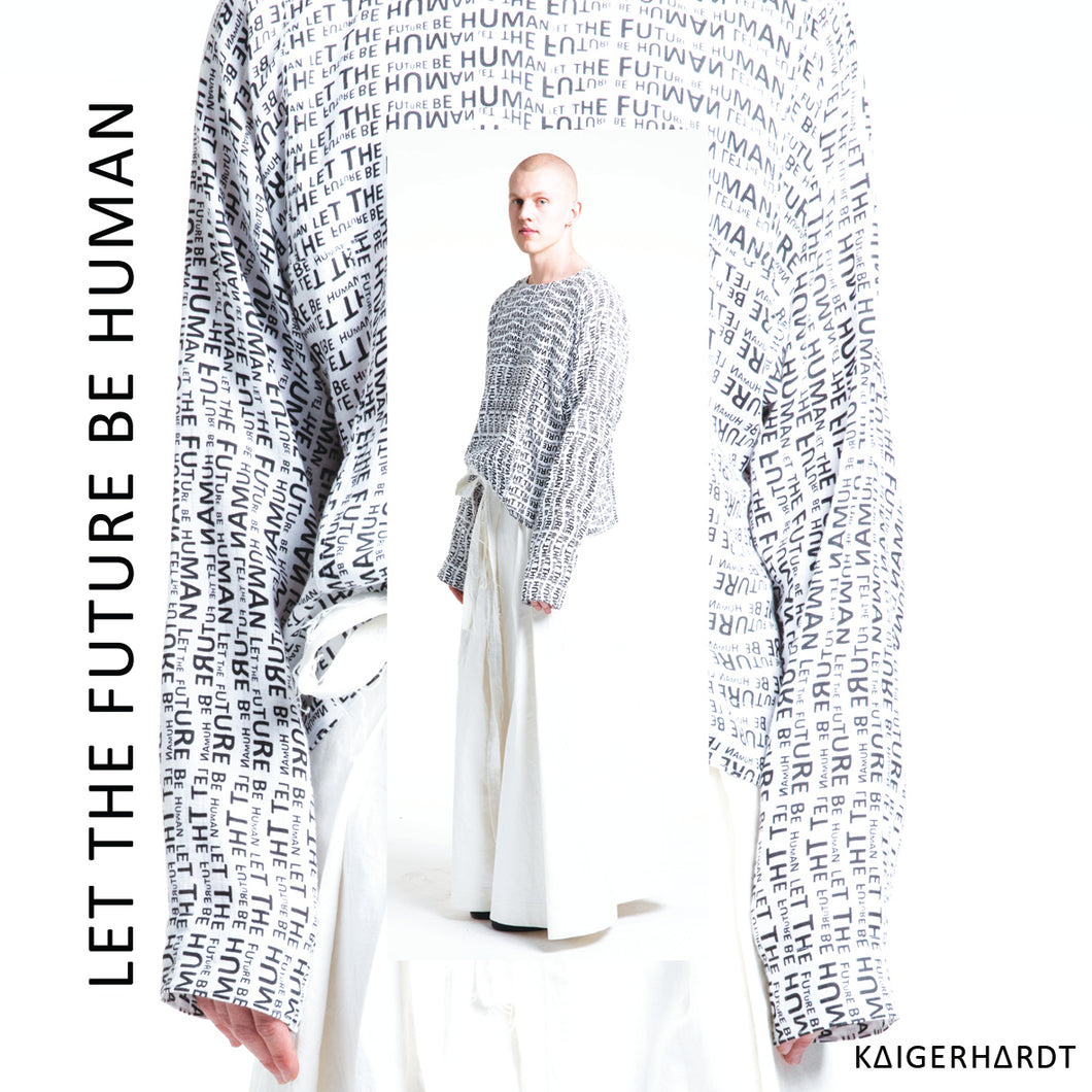 Paulius is wearing a white light sweater which has an all over print in small letters which says let the future be human. The sweater has long sleeves so that you only see the finger tips of the model. withe the sweater he wears a white long wide pair of trousers in hakama style made out of denim. 