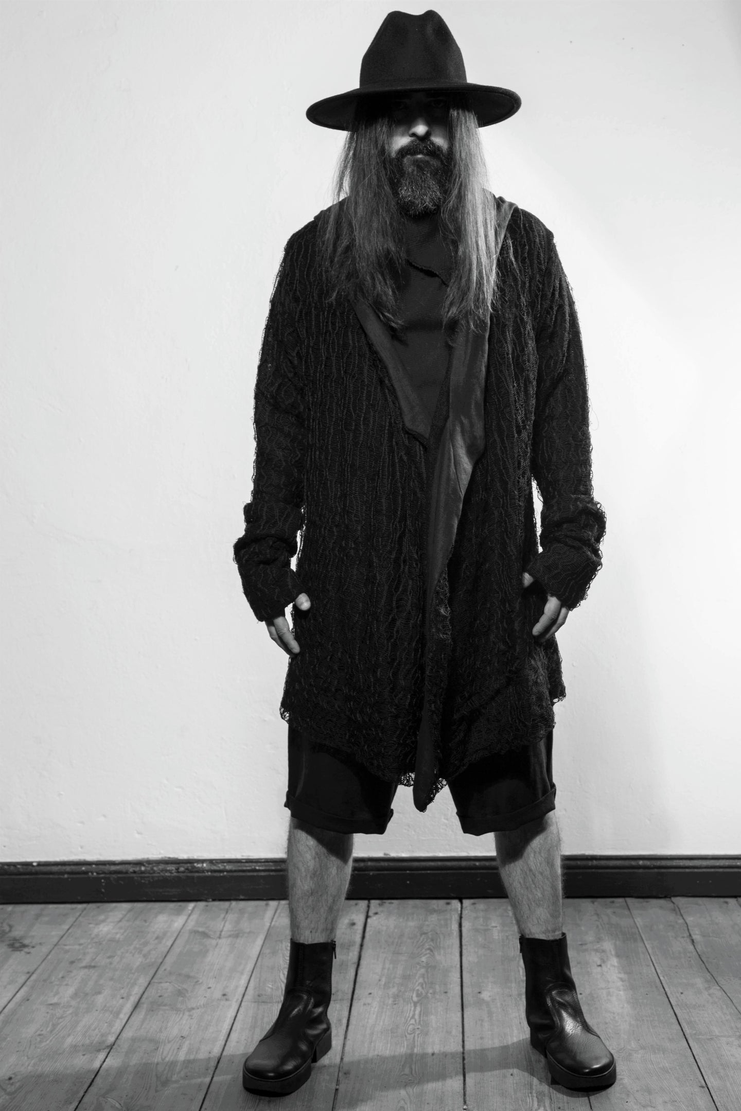 Front. A black draped cardigan in unregular grid optic with a crossing front. The cardigan is made in Berlin Germany    Colour: black Material: overgarment 100% PE                lining               80% wool, 20% cotton