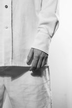Detailshoot. A classic shirt with raw-edges at the yoke in the back and the left side at the front, the inner layer are white at the cuffs, yoke and stand. The shirt is made in Berlin Germany.        Colour: white, black Material: 90% cotton, 10% linen