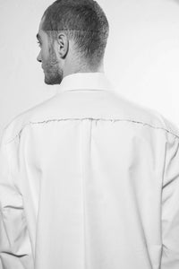 Detailshoot. A classic shirt with raw-edges at the yoke in the back and the left side at the front, the inner layer are white at the cuffs, yoke and stand. The shirt is made in Berlin Germany.        Colour: white, black Material: 90% cotton, 10% linen